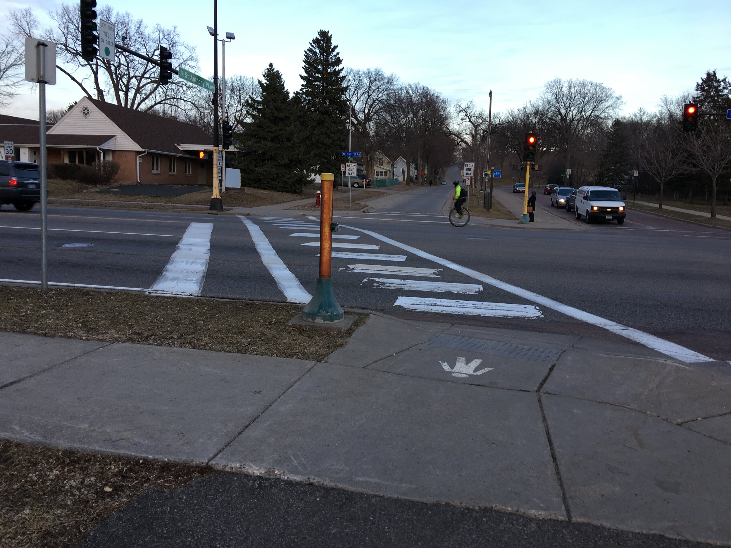 An intersection that attempts to be pedestrian friendly but offers no medians along the wide four lane traffic (also a unicyclist commuting home)